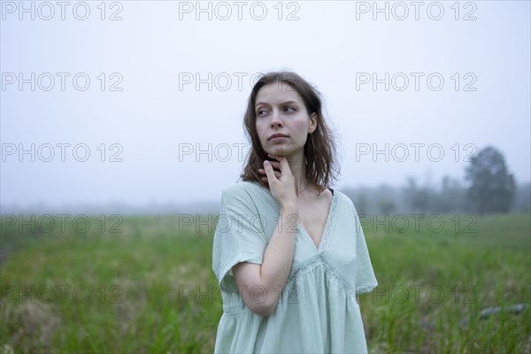 Portrait of thoughtful woman in meadow on foggy day