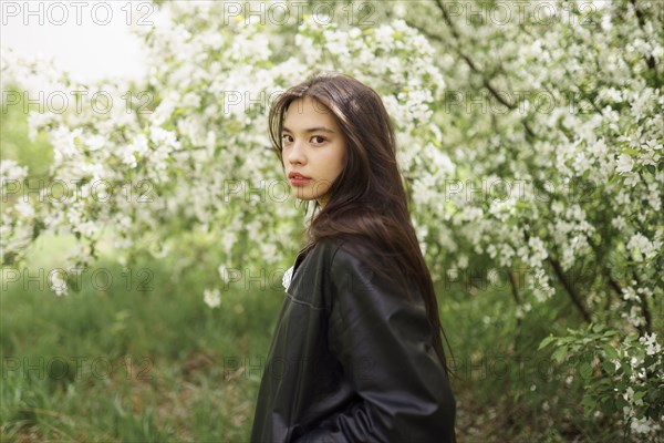 Portrait of teenage girl against blooming apple tree