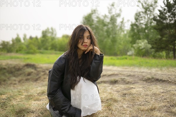 Portrait of teenage girl crouching in nature