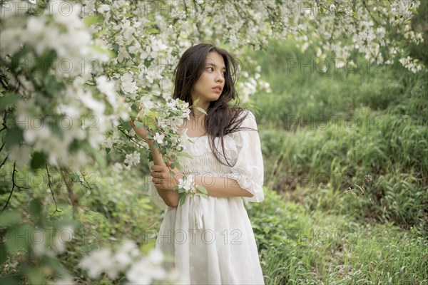 Portrait of teenage girl with blooming apple tree