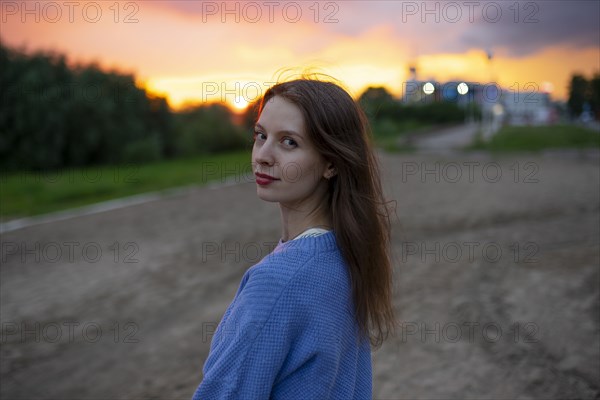 Portrait of beautiful woman standing in field at sunset
