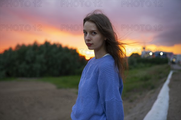 Portrait of beautiful woman standing in field at sunset