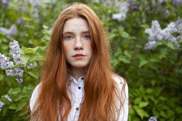 Portrait of serious teenage girl against lilac bush