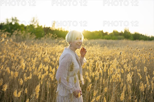 Portrait of woman standing in field at sunset