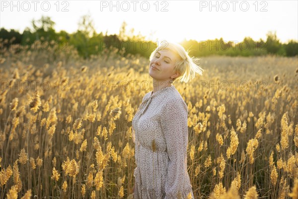 Portrait of woman standing in field at sunset