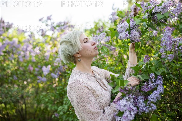 Portrait of woman smelling lilac flowers in garden