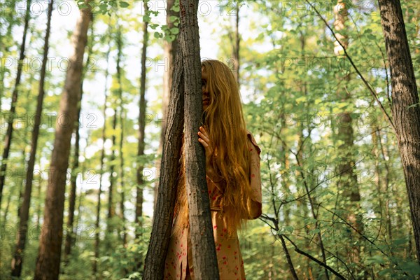 Young woman touching tree in forest