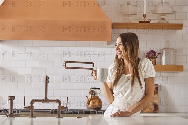 Smiling woman holding mug in kitchen