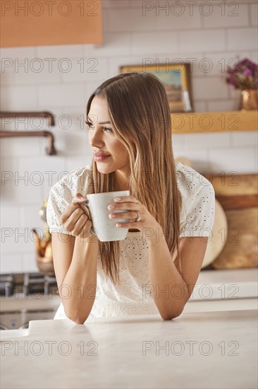 Smiling woman holding mug in kitchen