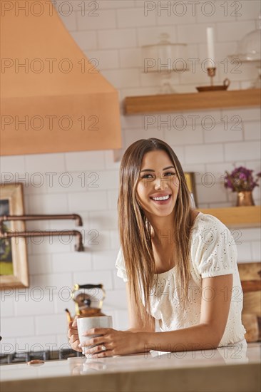 Smiling woman holding mug in kitchen