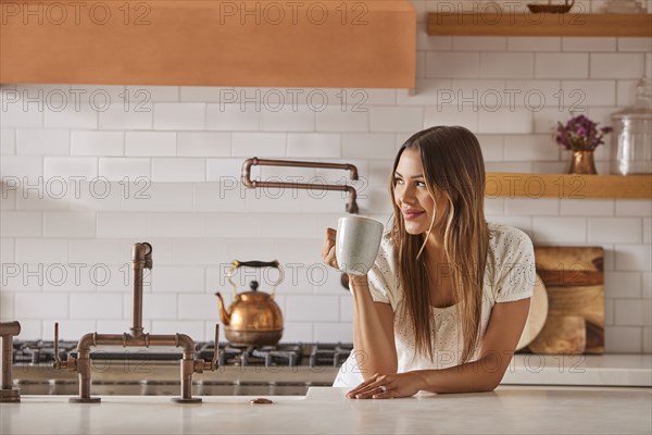 Smiling woman holding mug in kitchen