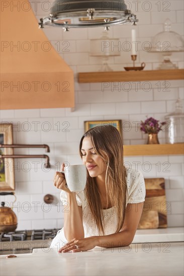 Smiling woman holding mug in kitchen