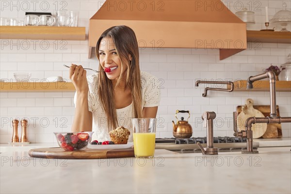 Portrait of smiling woman enjoying healthy breakfast in kitchen