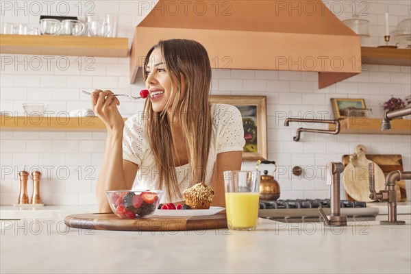 Smiling woman enjoying healthy breakfast in kitchen