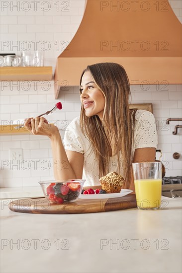 Smiling woman enjoying healthy breakfast in kitchen