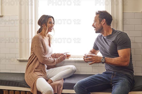 Smiling couple relaxing by window at home