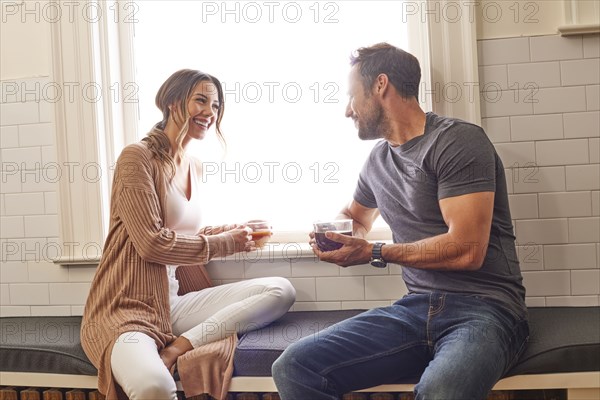 Smiling couple relaxing by window at home