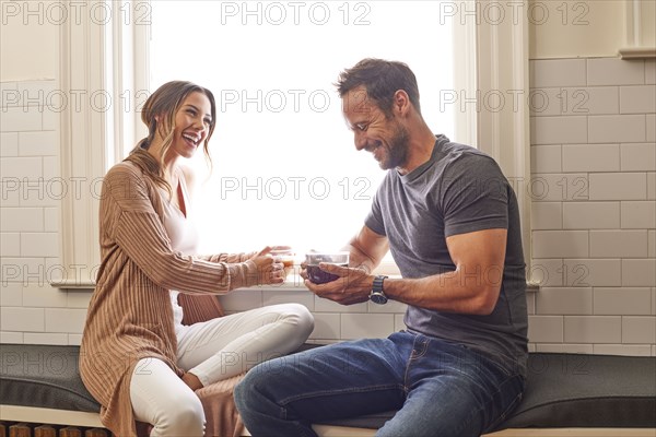 Smiling couple relaxing by window at home