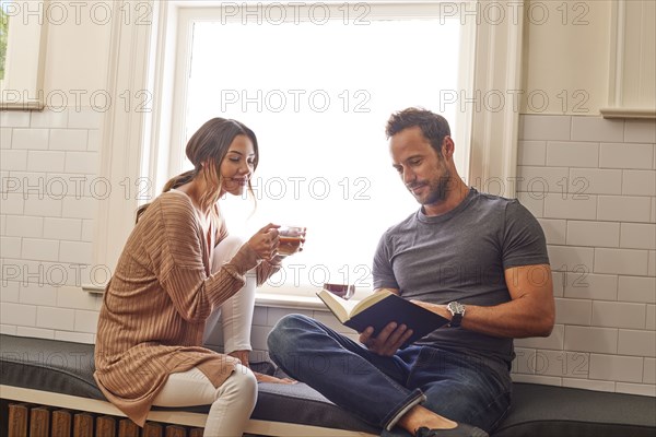 Smiling couple relaxing by window at home