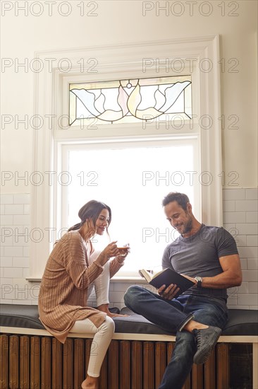 Smiling couple relaxing by window at home