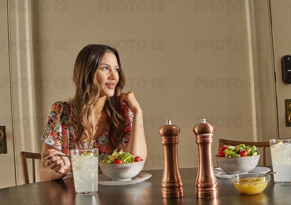 Smiling woman enjoying salad at table at home