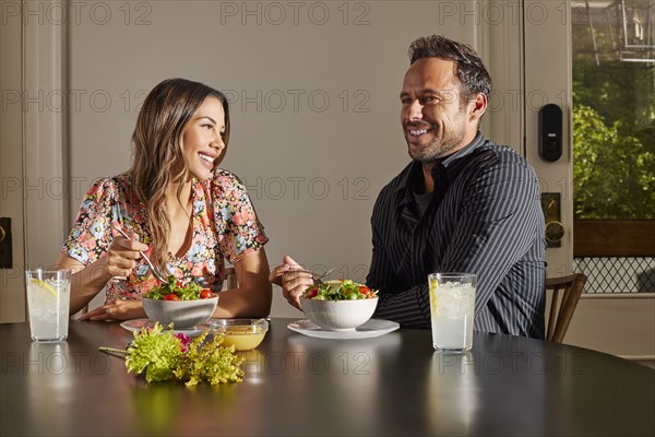 Smiling couple enjoying salad at table at home