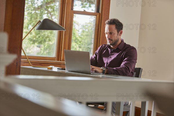 Man using laptop at table at home