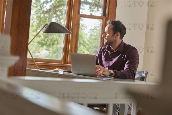 Man using laptop at table at home