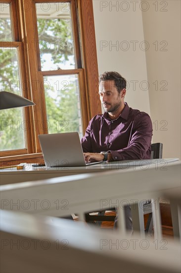 Man using laptop at table at home