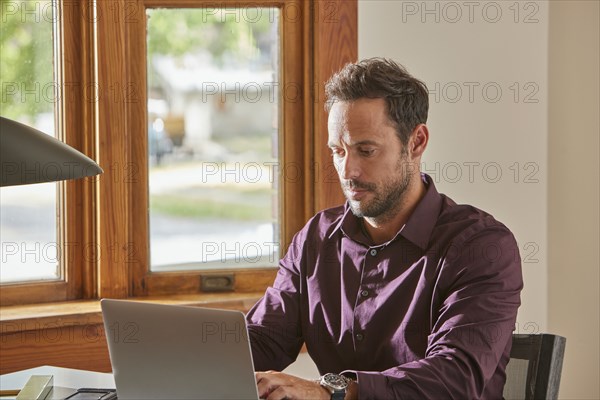 Man using laptop at desk at home