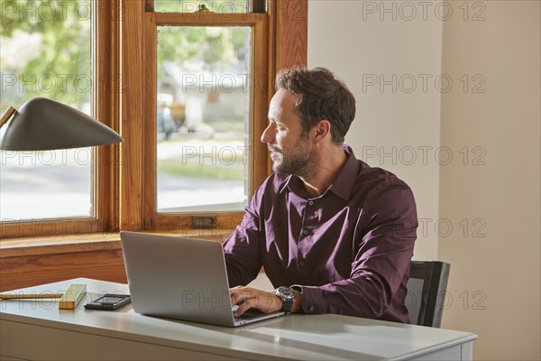 Man using laptop at desk at home