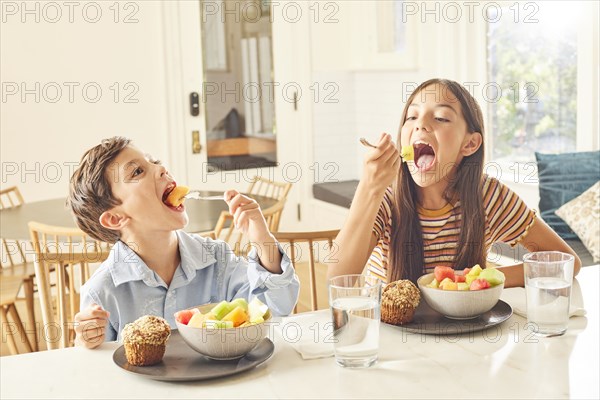 Boy and girl eating breakfast in kitchen