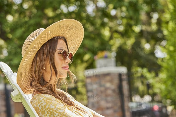 Woman in straw hat and sunglasses relaxing in park