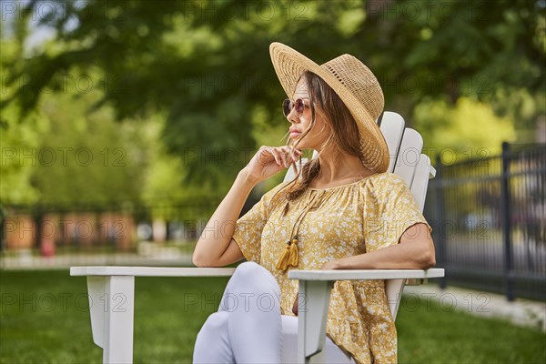 Woman in straw hat and sunglasses relaxing in park