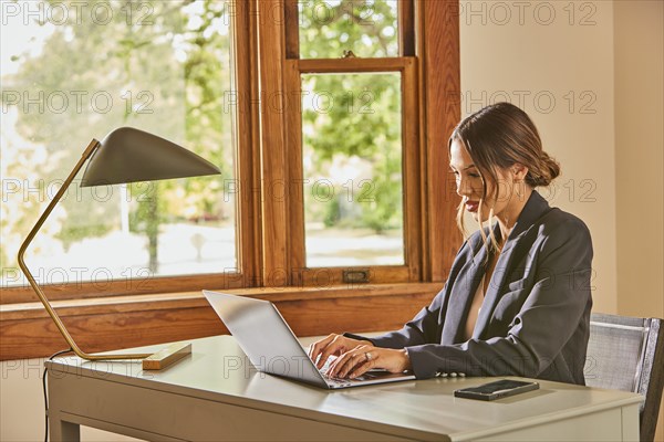 Woman using laptop and at desk at home