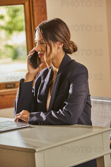 Smiling woman using smart phone at desk at home