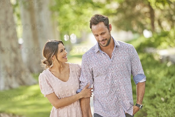 Smiling couple walking on treelined sidewalk