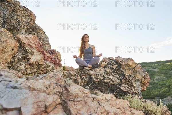 Mid adult woman meditating in mountains