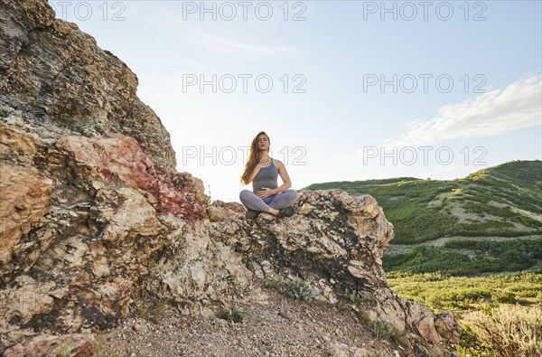 Mid adult woman meditating in mountains