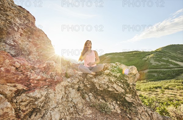 Mid adult woman meditating in mountains