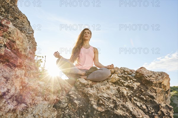 Mid adult woman meditating in mountains