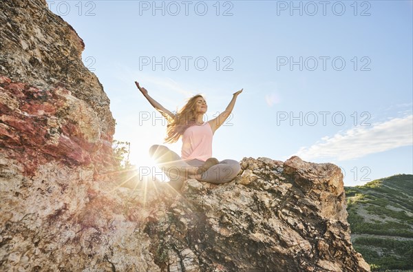 Mid adult woman meditating in mountains