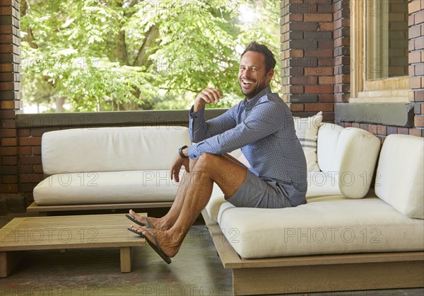 Mid adult man relaxing on sofa on patio