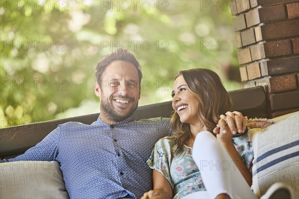 Mid adult couple relaxing on sofa on patio