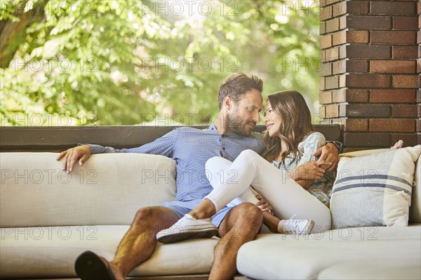 Mid adult couple relaxing on sofa on patio