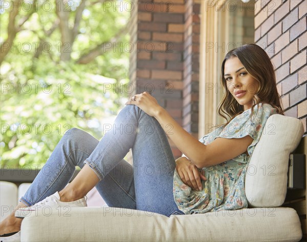 Portrait of mid adult woman relaxing on sofa on patio