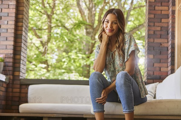 Portrait of mid adult woman relaxing on sofa on patio