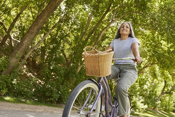 Smiling mature woman riding bicycle in park