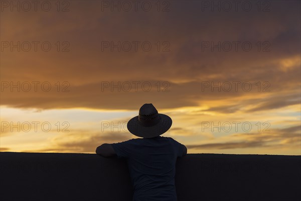 Silhouette of man in hat looking at sunset