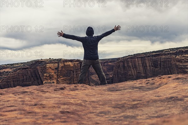 Man spreading arms in canyon